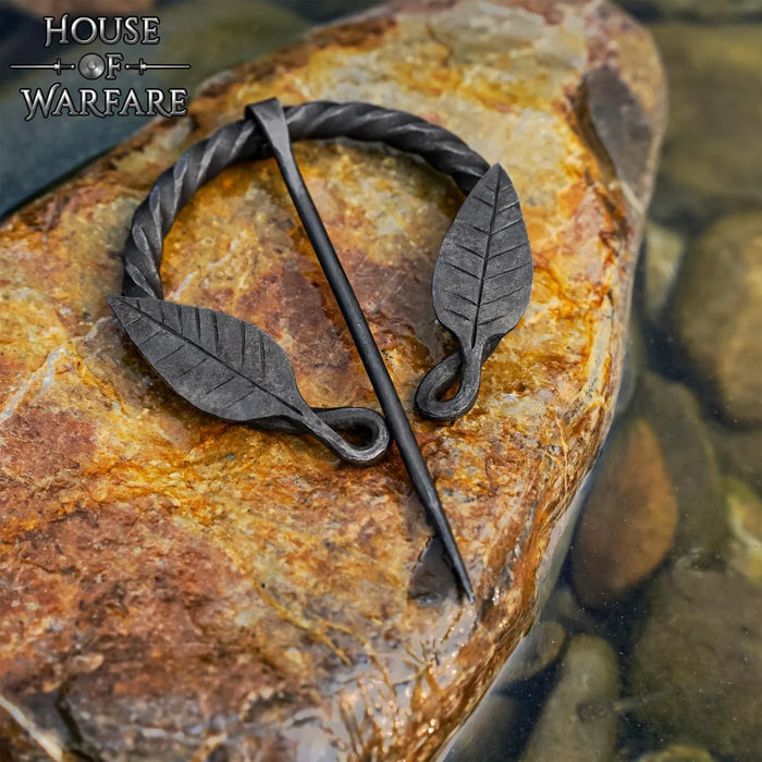 Fibula a ferro di cavallo ritorta con motivo a foglia, ferro